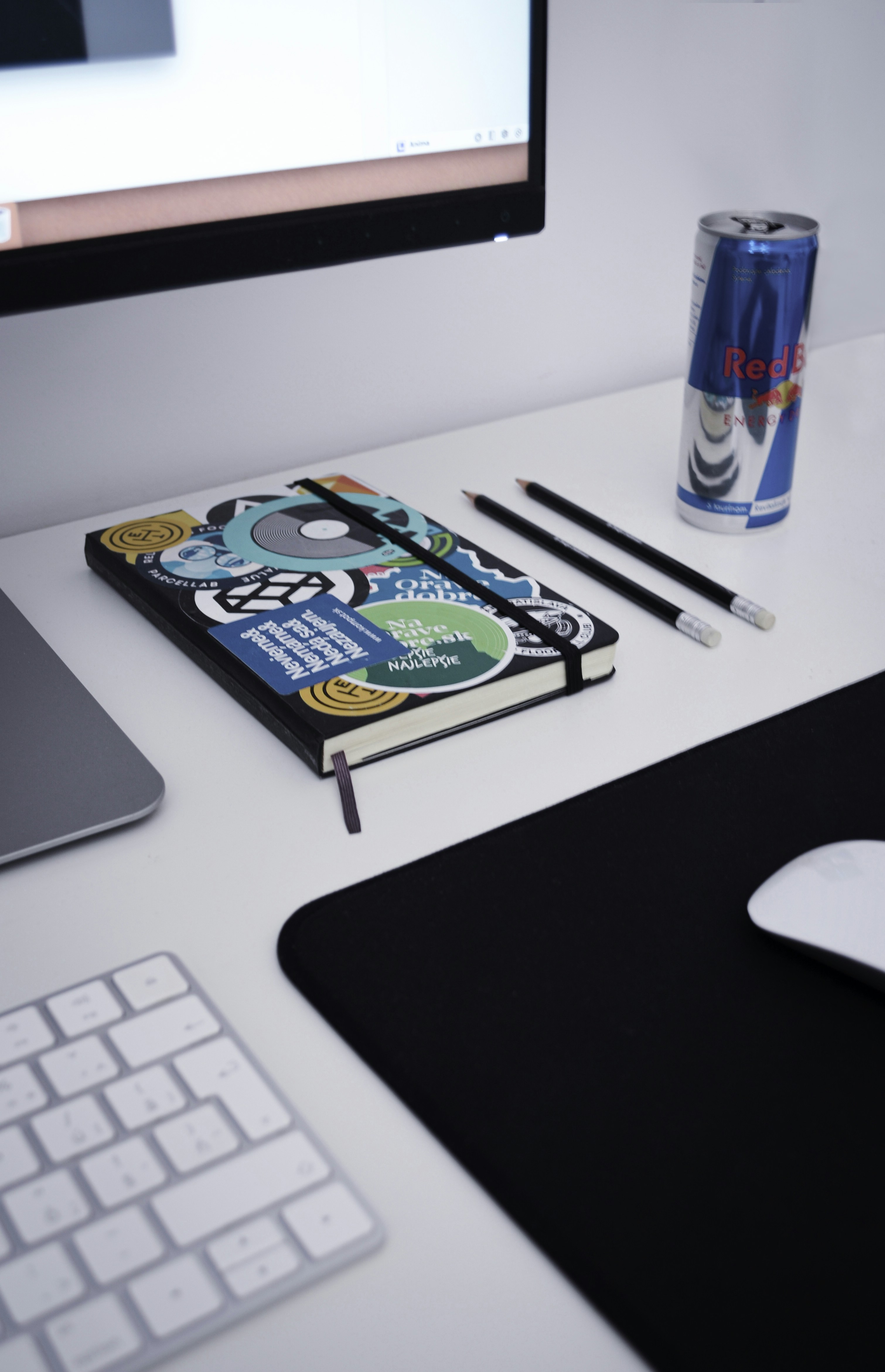 book beside two pens and Red Bull can on table