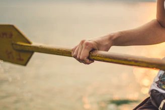 Close-up of a kayaker gripping a paddle, water droplets glistening in the sunlight.