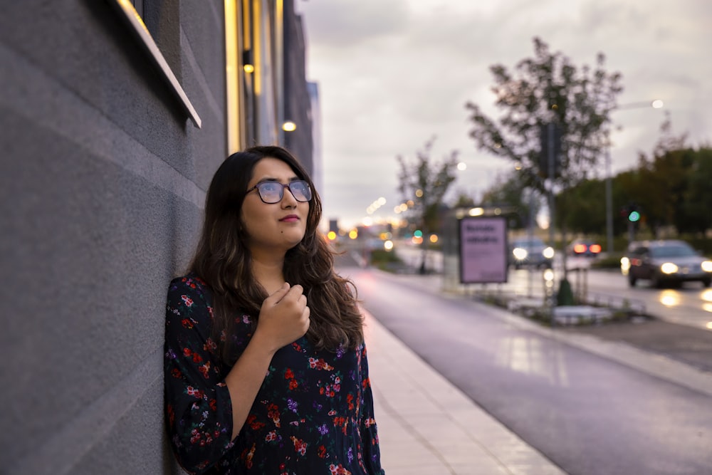 woman leaning on gray wall looking up