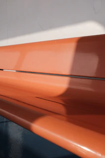 A vibrant orange Nuifit t-shirt laid out on a wooden bench with morning sunlight casting soft shadows.