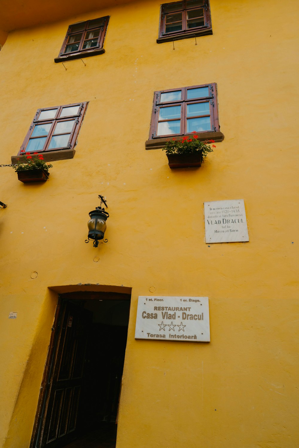 a yellow building with three windows and a sign on the side