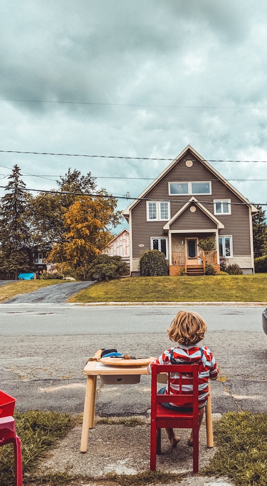 boy sitting on red chair facing near house in Magog Canada