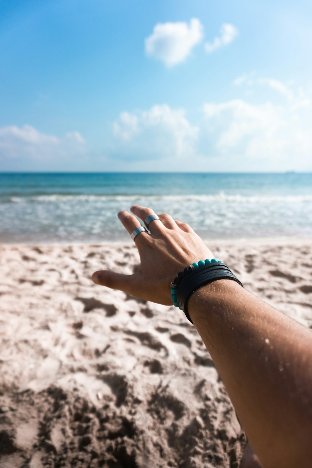 Person, die tagsüber ein schwarz-silbernes Armband am Strand trägt