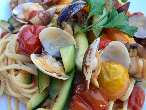 Close-up of a steaming plate of spaghetti with tomato sauce and fresh herbs.