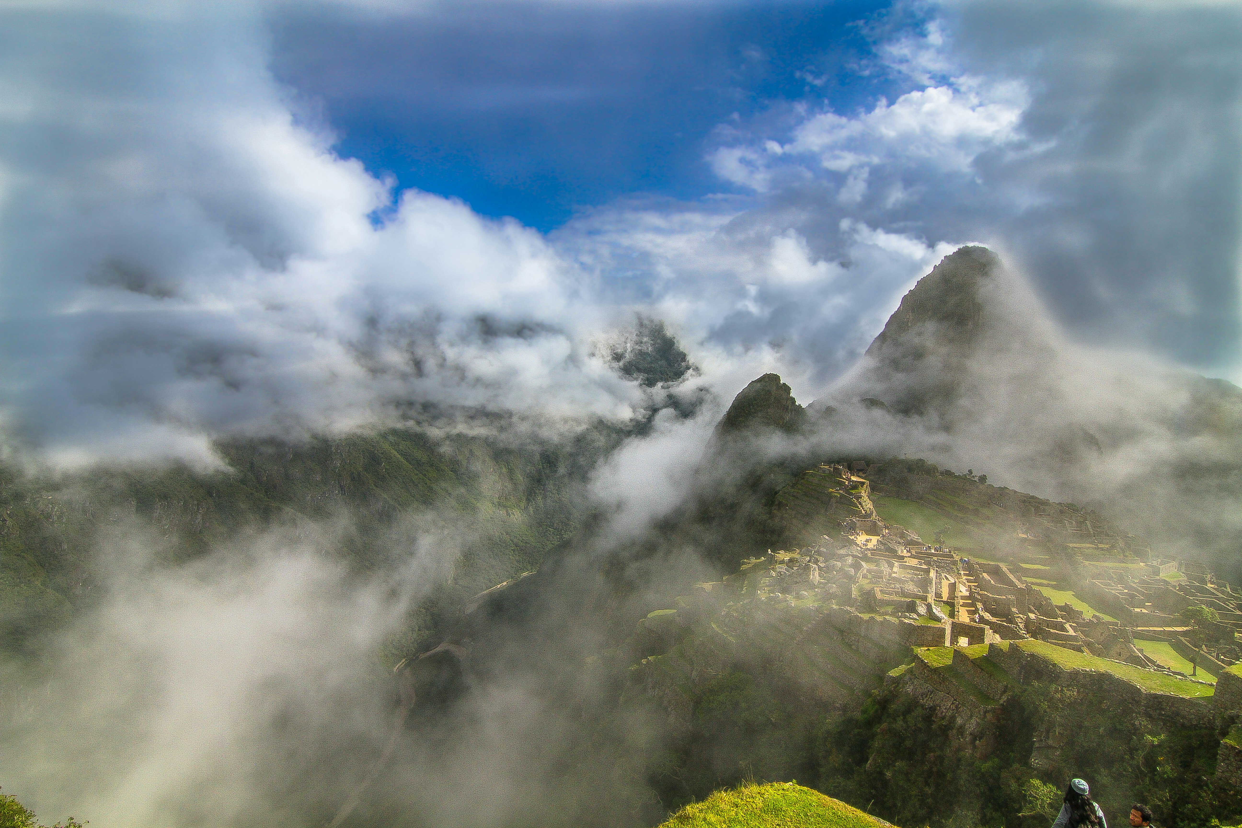 Ancient Machu Picchu citadel emerging from dramatic mountain clouds, dark stone ruins, misty Andean landscape