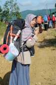 woman wearing gray headscarf carrying black backpack