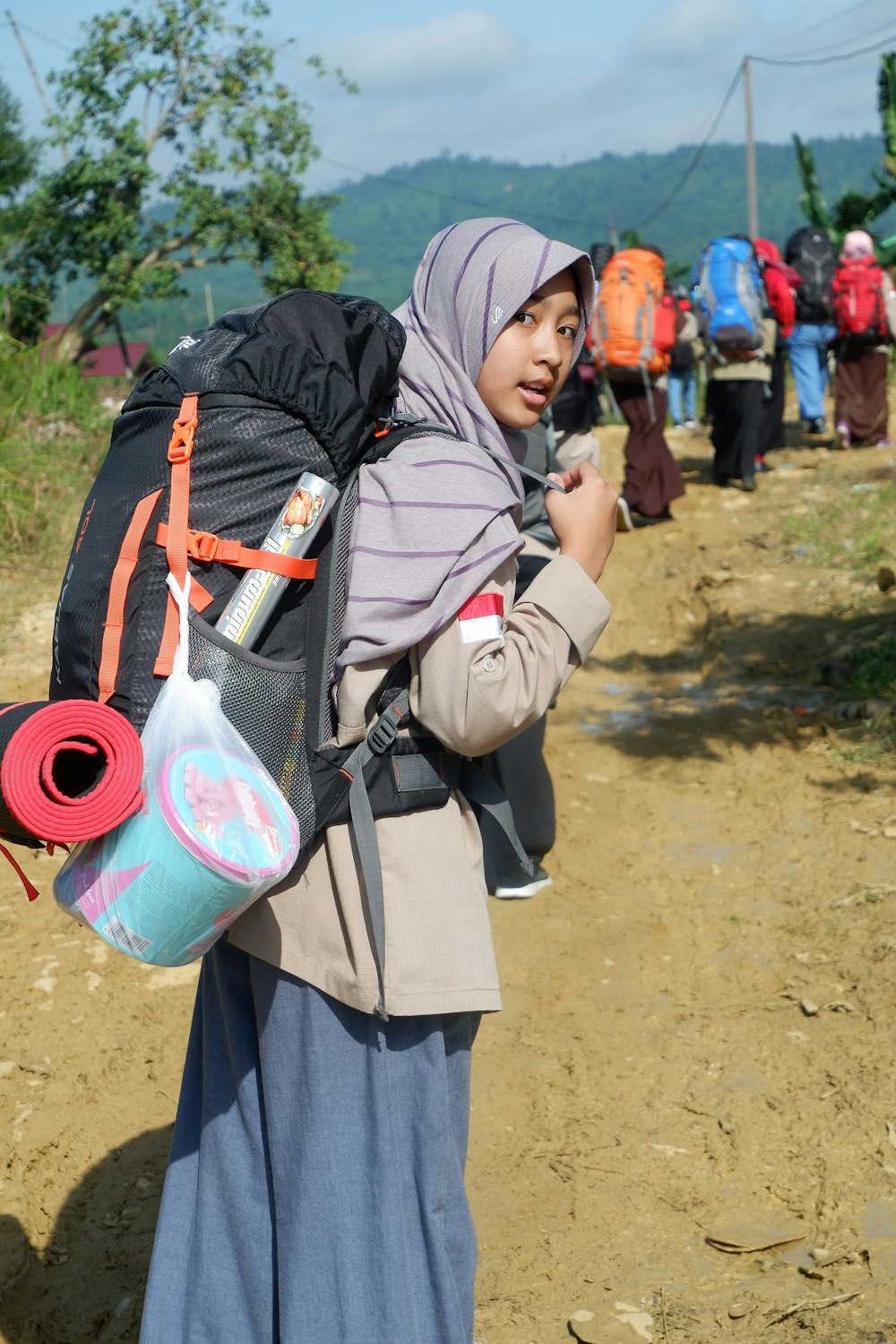 woman wearing gray headscarf carrying black backpack