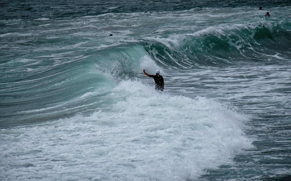 person wearing black wetsuit in the middle of ocean