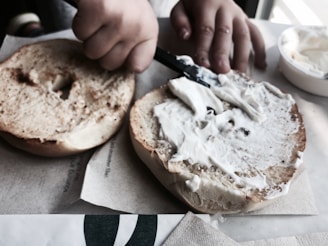 A smiling customer enjoying a bagel with cream cheese at a small café table.