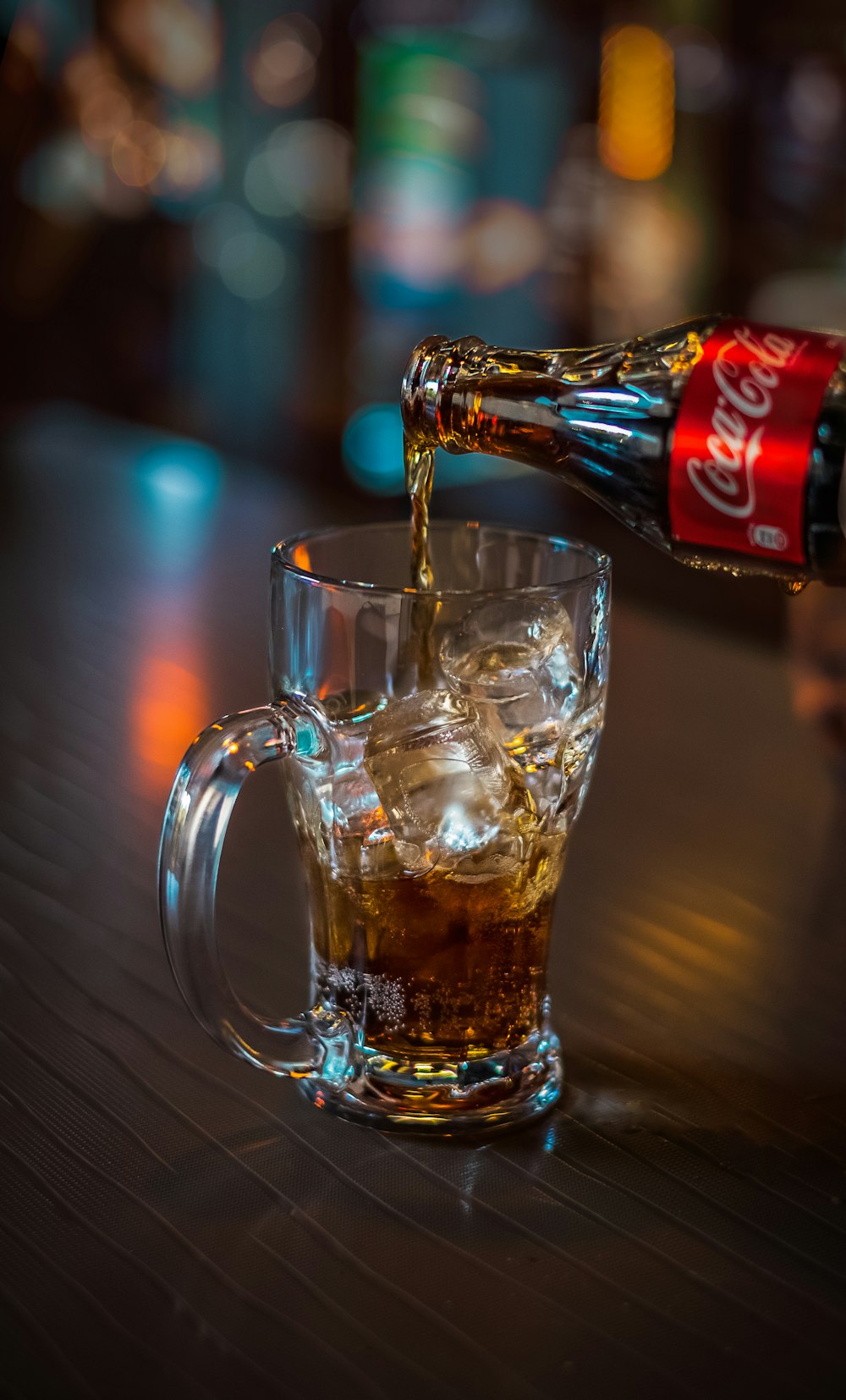 Coca-Cola soda pouring onto clear glass mug