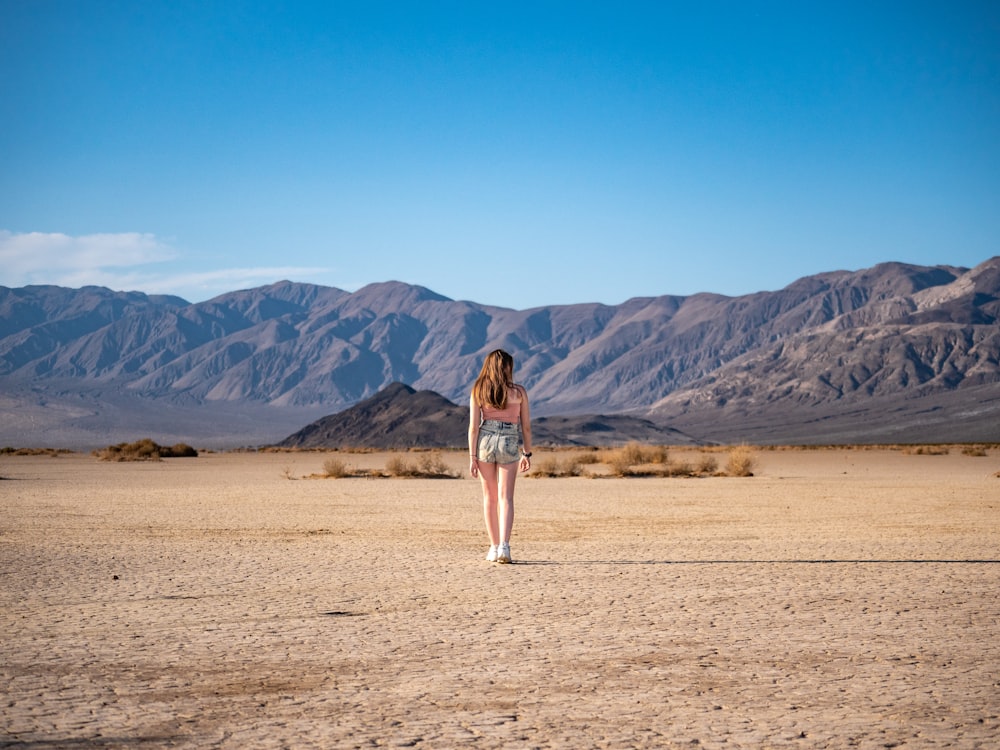woman standing on desert under blue and white skies during daytime