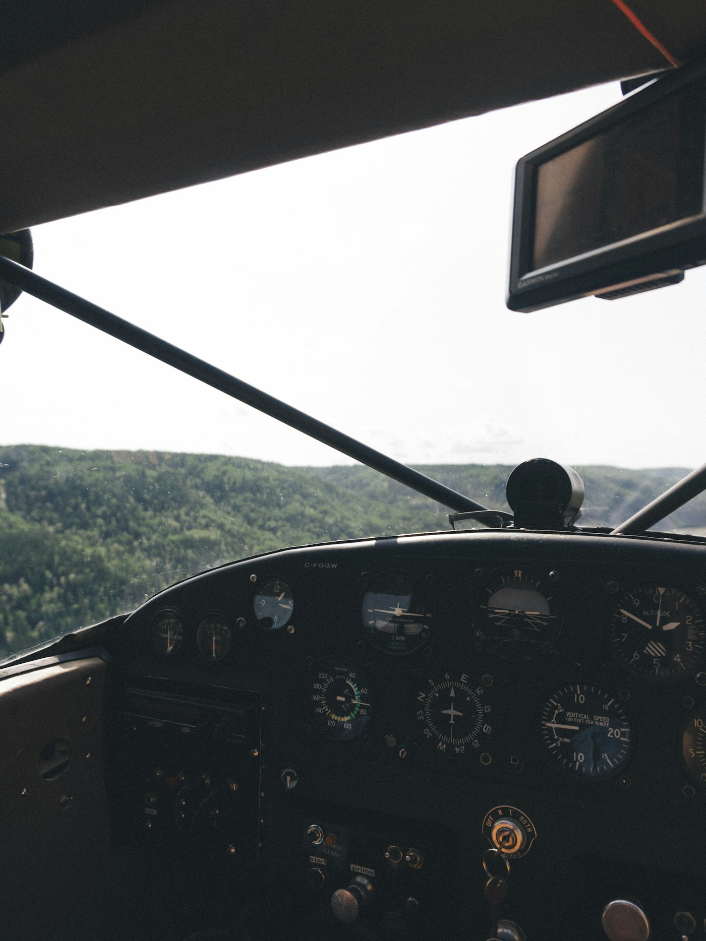 The instrument panel of a small aircraft in flight, green countryside through the windscreen