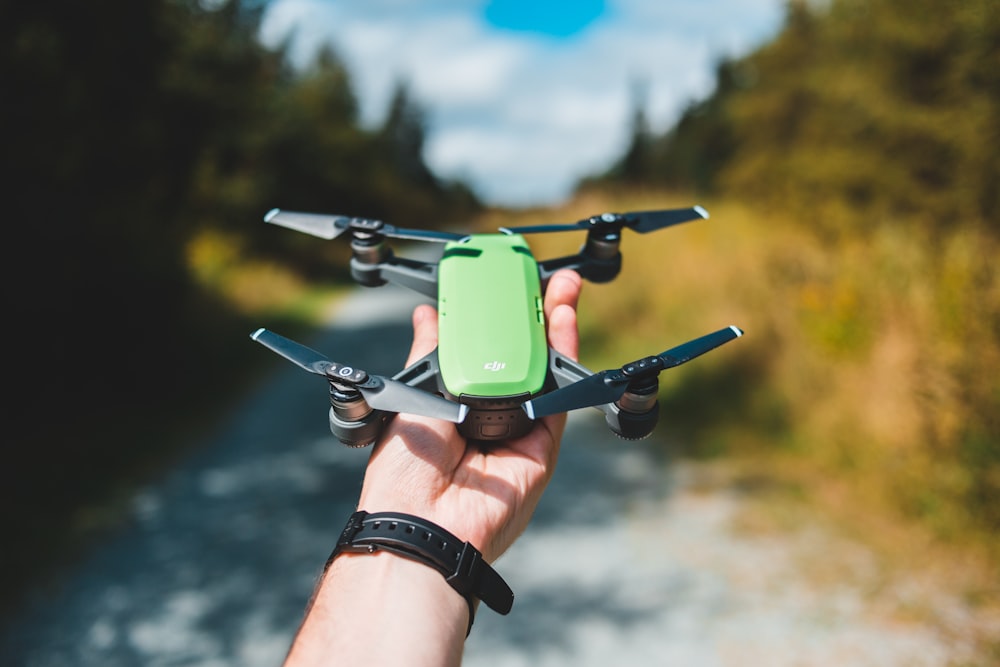 person holds green and black drone