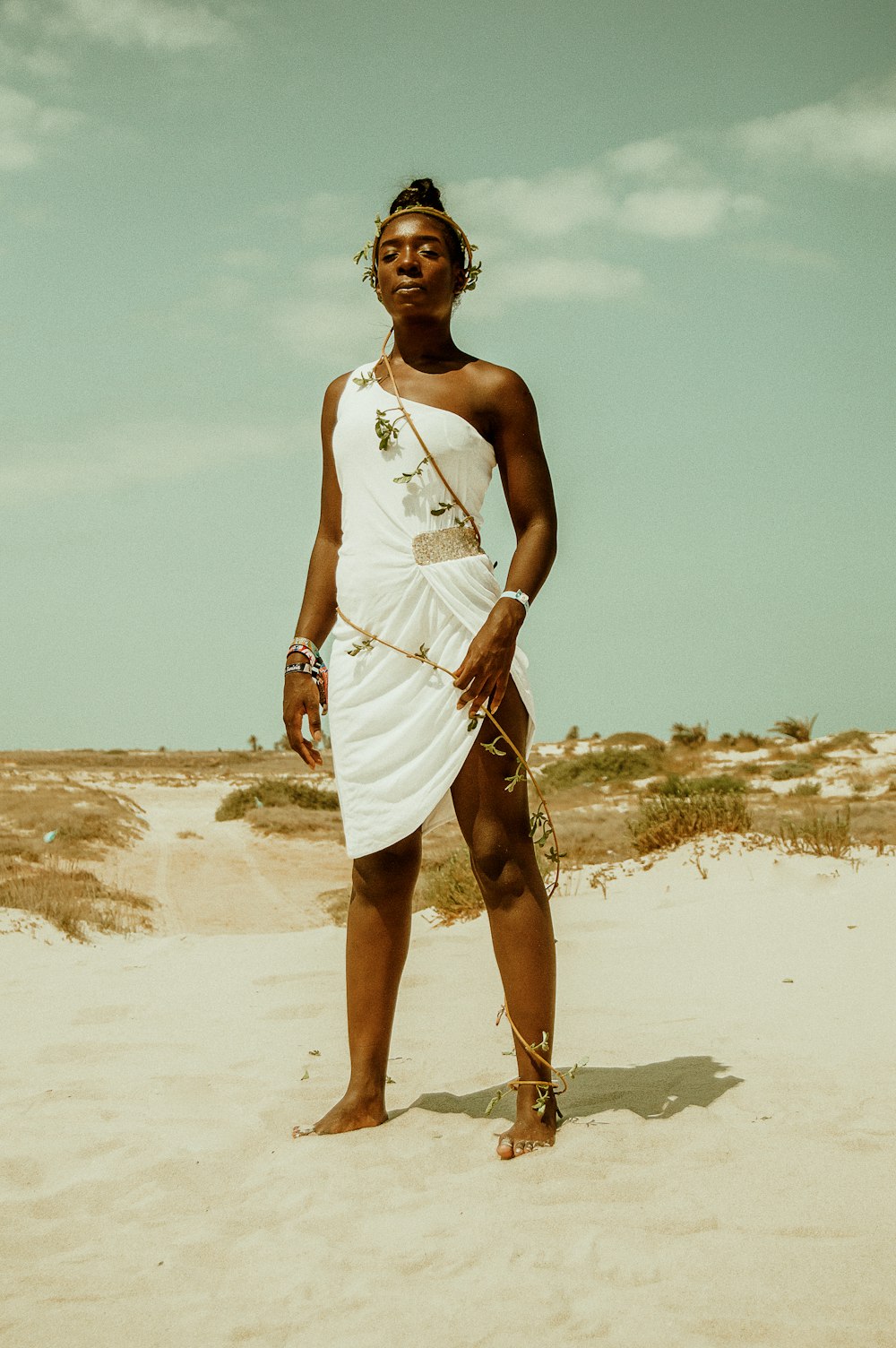 woman wearing white one-shoulder dress standing on sand