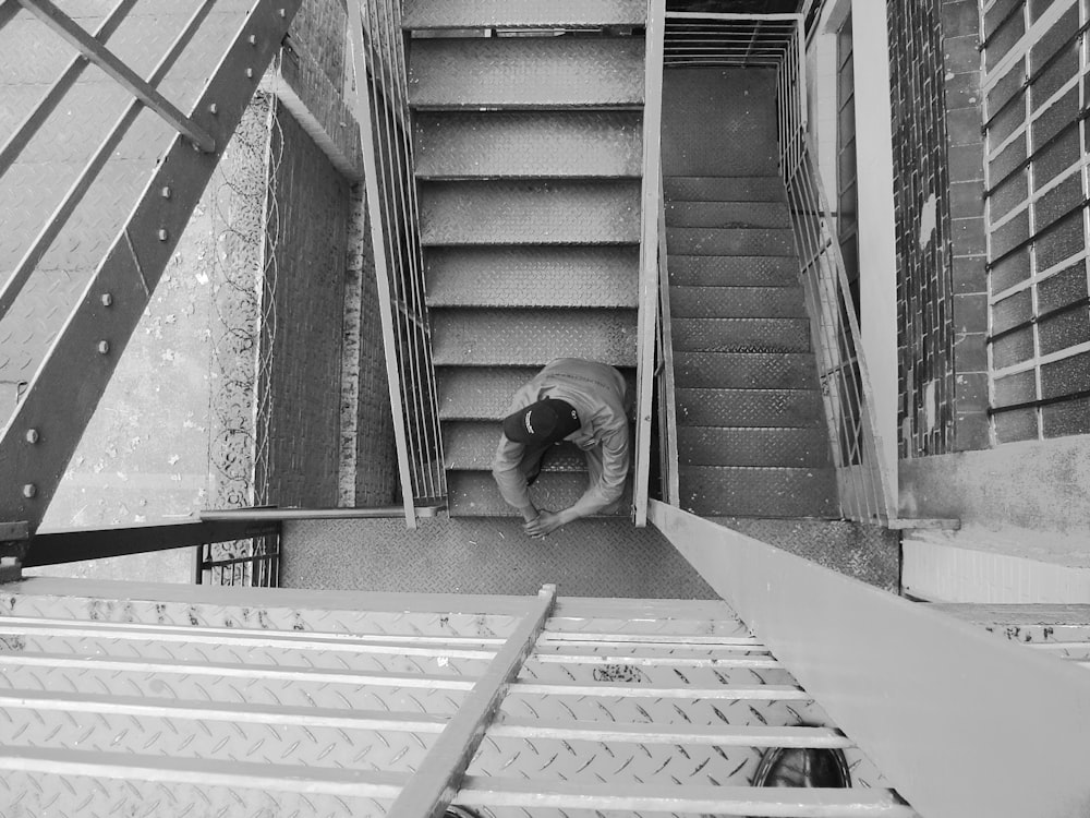 grayscale photo of man sitting on stair