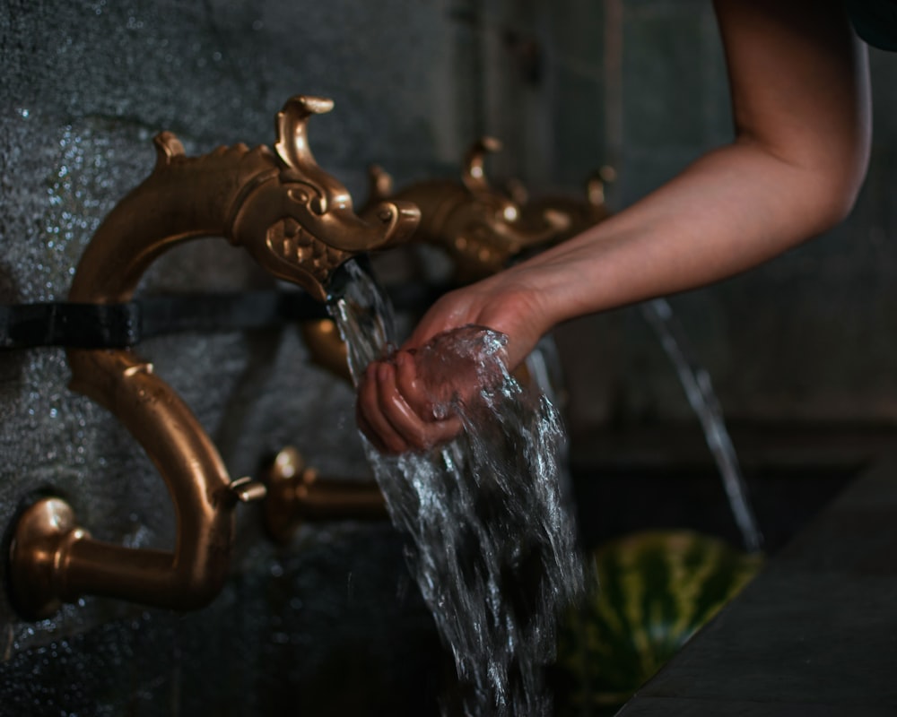 person washing hand on flowing water