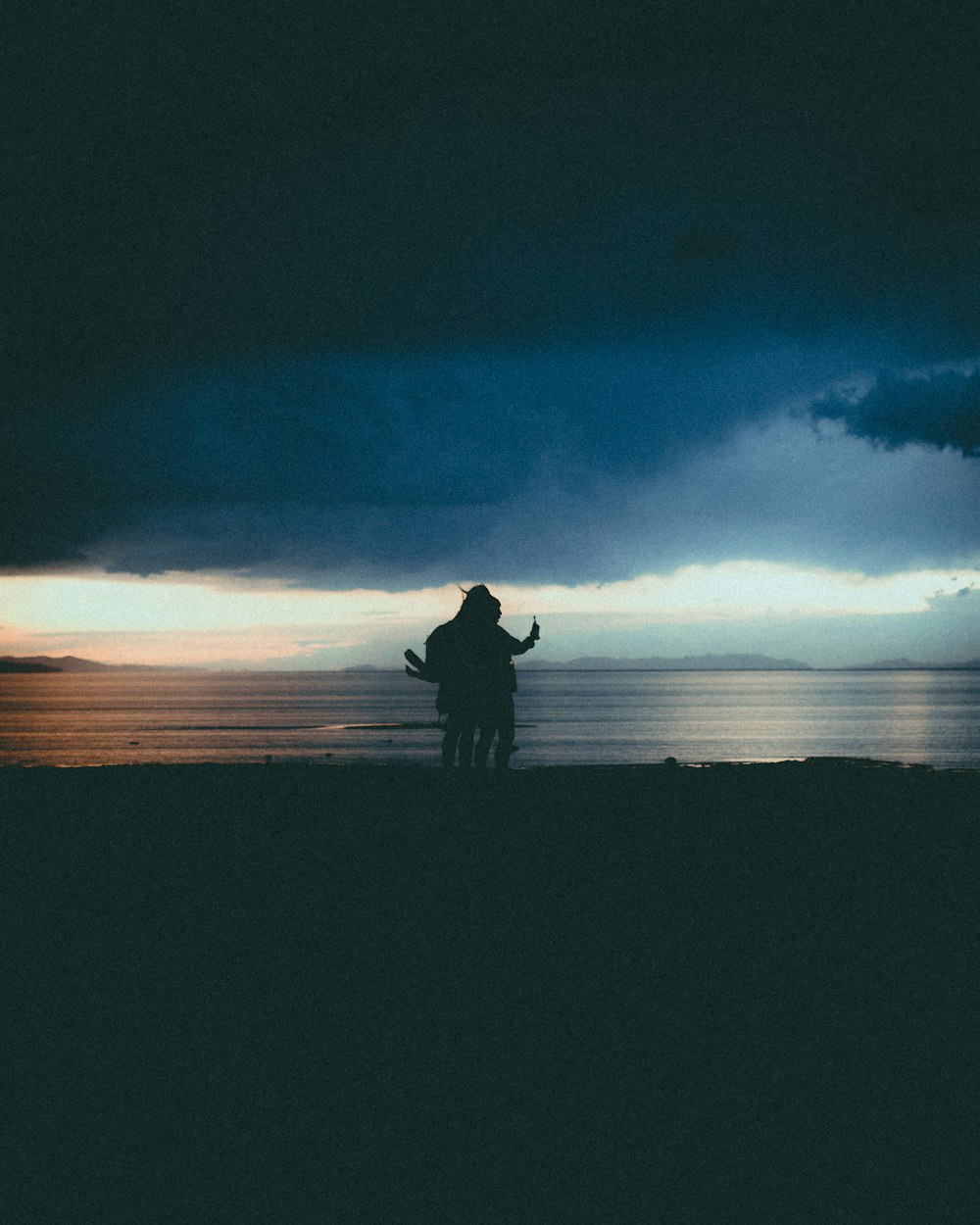 silhouette of man and woman standing on field during night time