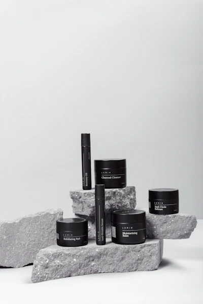 Black skincare jars arranged on rough grey stone blocks