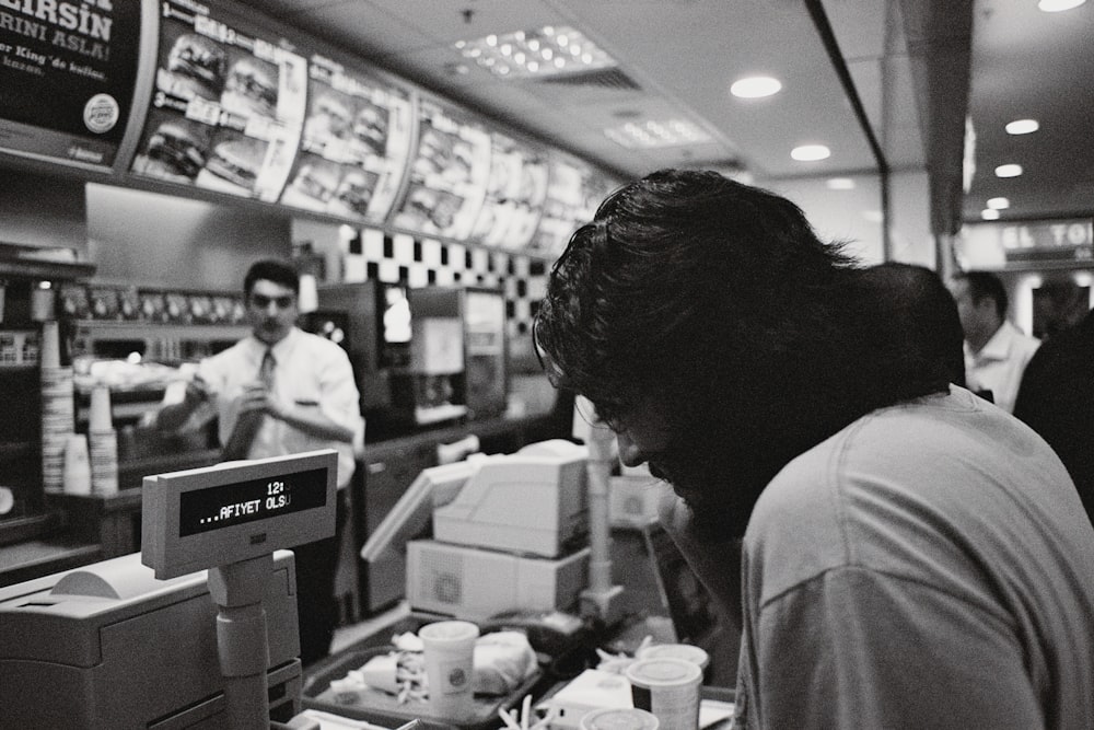 a black and white photo of a man at a fast food restaurant