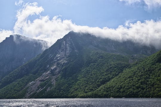 lake viewing mountain under blue and white skies during daytime in Norris Point Canada