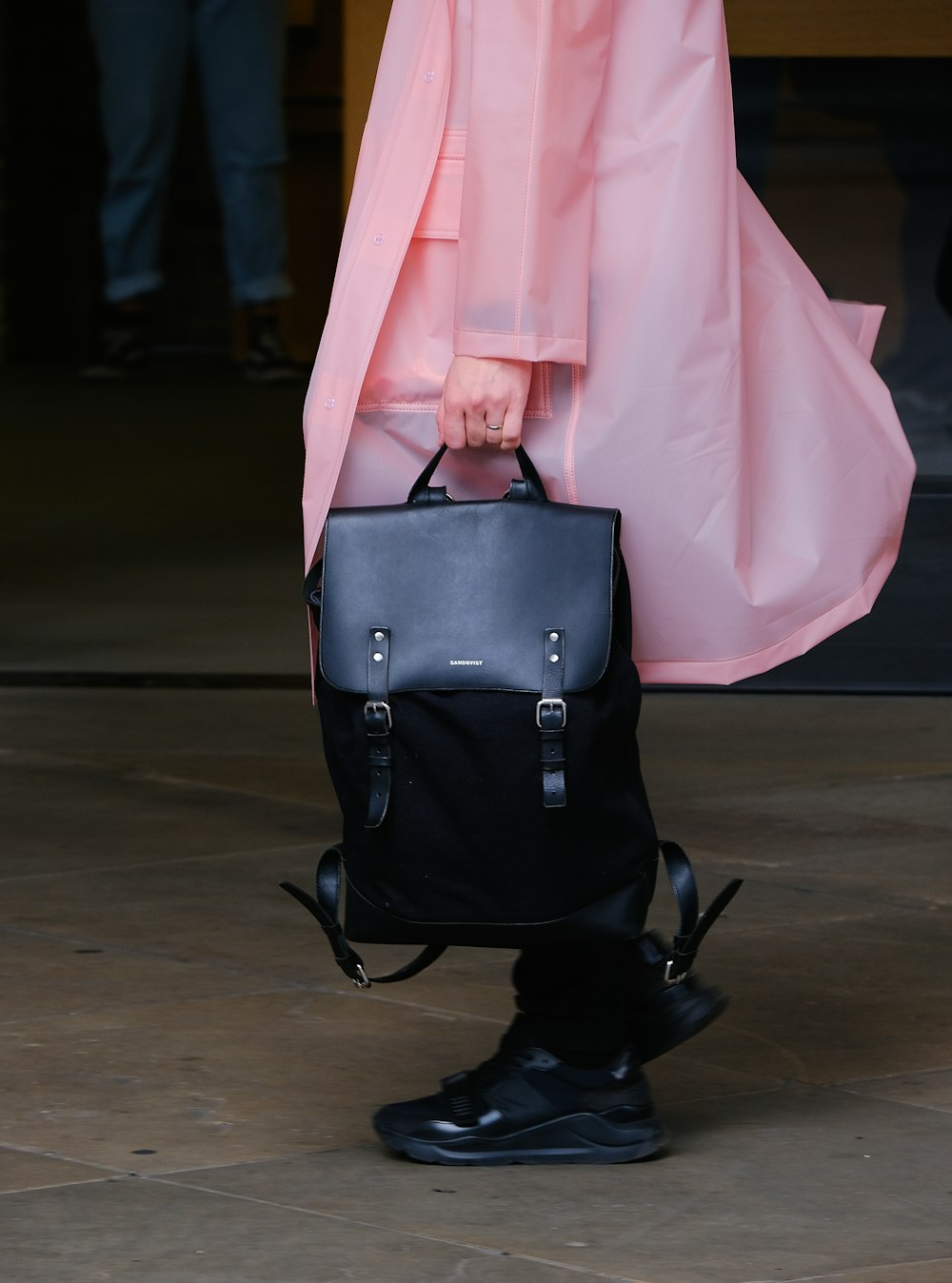 person in pink coat holding leather bag