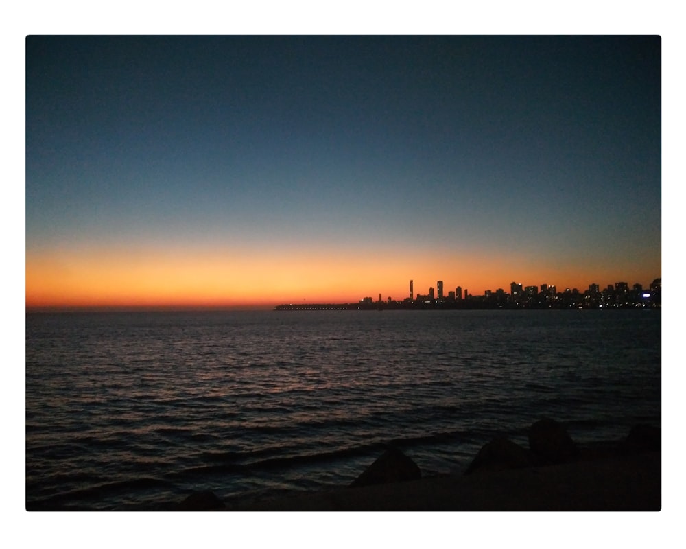 body of water across city buildings during dusk