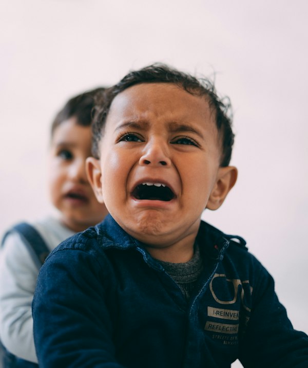 A parent gently holding a young child's hand after a difficult moment