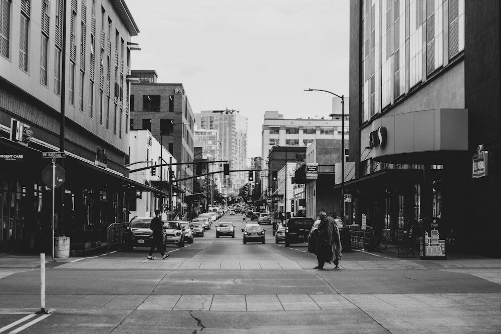 ストリートビューイング車両や建物の近くを歩く人々のグレースケール写真