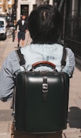 A traveler carrying a leather bag in an urban setting.