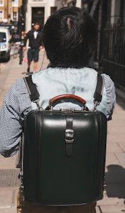 Close-up of hands adjusting a stylish, minimalist backpack on a busy street corner.
