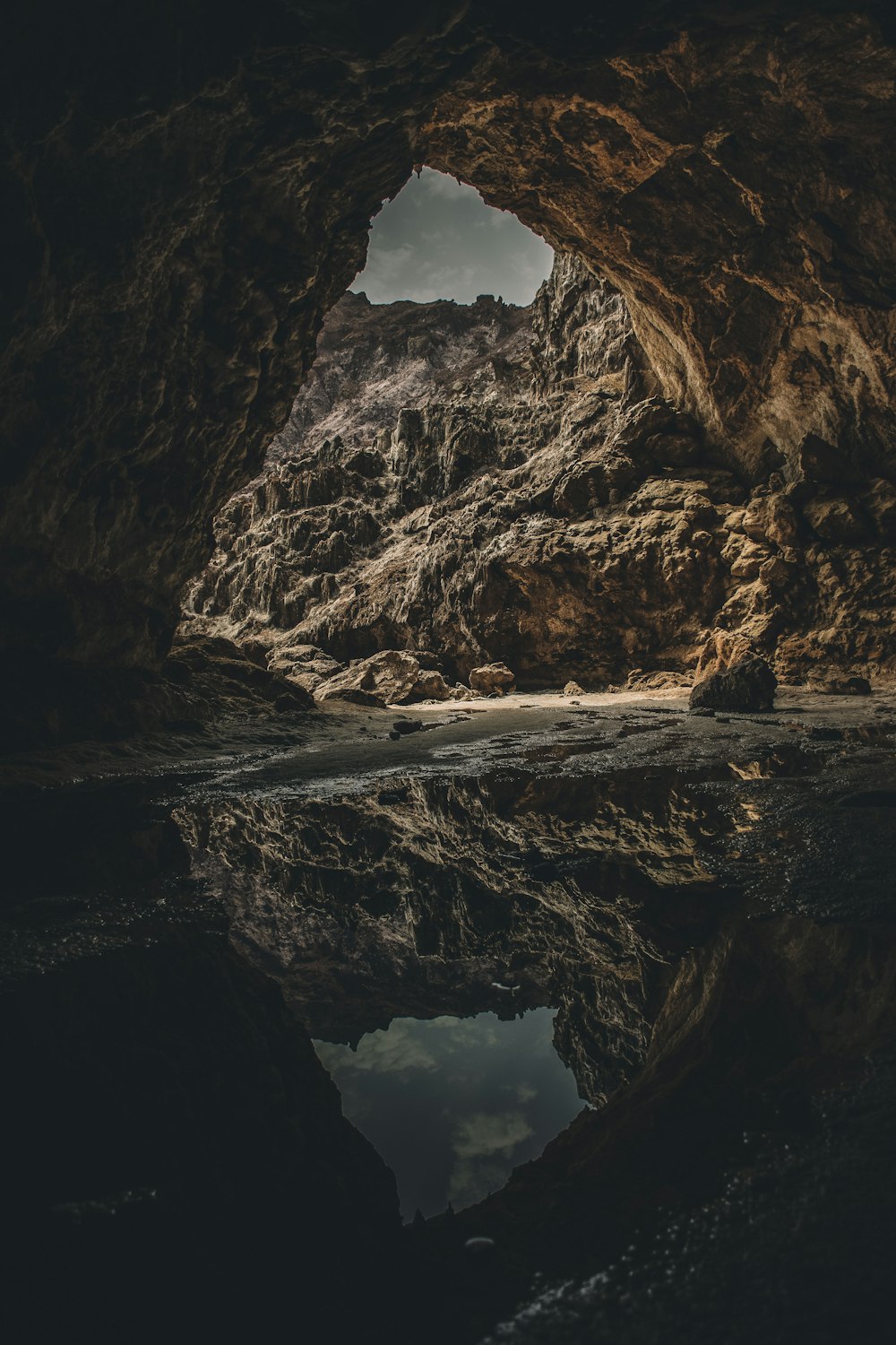 reflection of brown cave on body of water