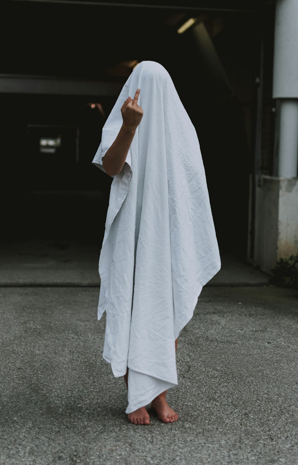 person covered in white textile showing middle finger