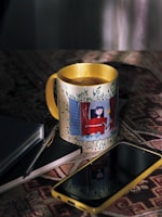 Phone case with a vibrant abstract art design lying next to a notebook and pen.