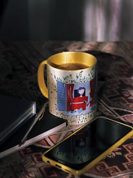 Bright coffee cup beside a notebook and smartphone.