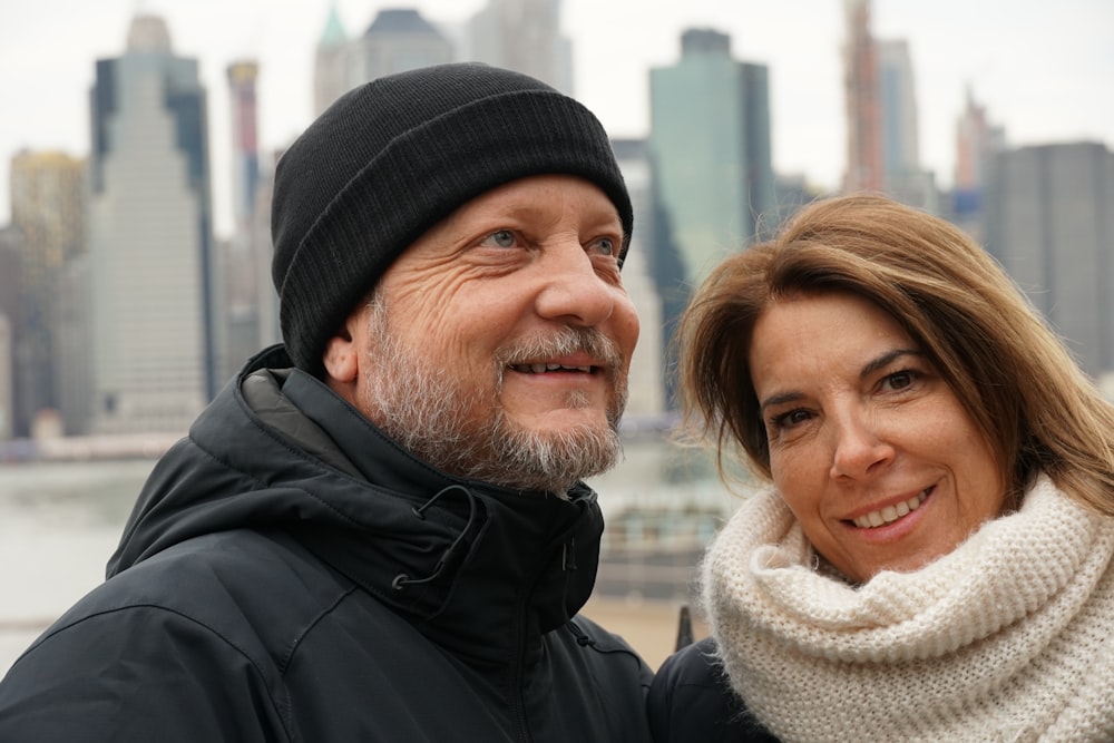 man and woman wearing coats standing near water