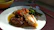 A man enjoying a beautifully plated homemade meal at a warmly lit dining table.