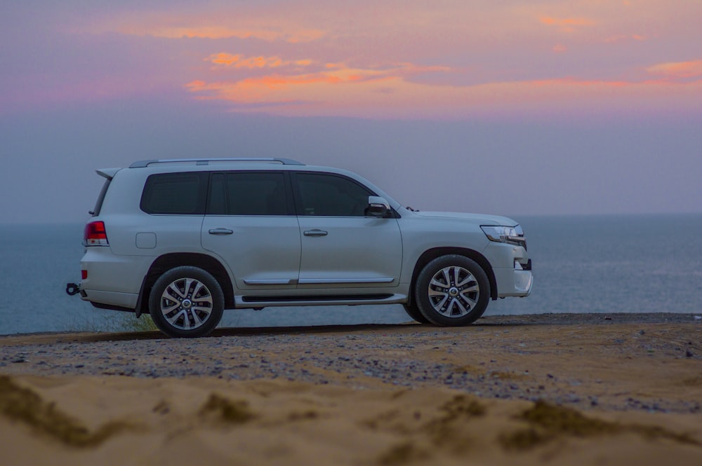 white SUV parked beside sea