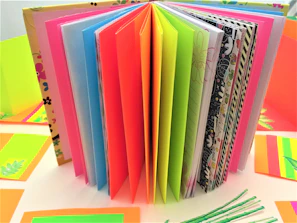 An open scrapbook showing layered collages of pastel papers, textured elements, and charming handwritten notes.