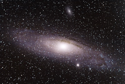 A vibrant spiral galaxy glowing in shades of violet and blue, sprinkled with twinkling stars.