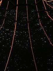 A dark space filled with small star-like lights scattered throughout, intersected by glowing orange lines that converge at a central circular structure.