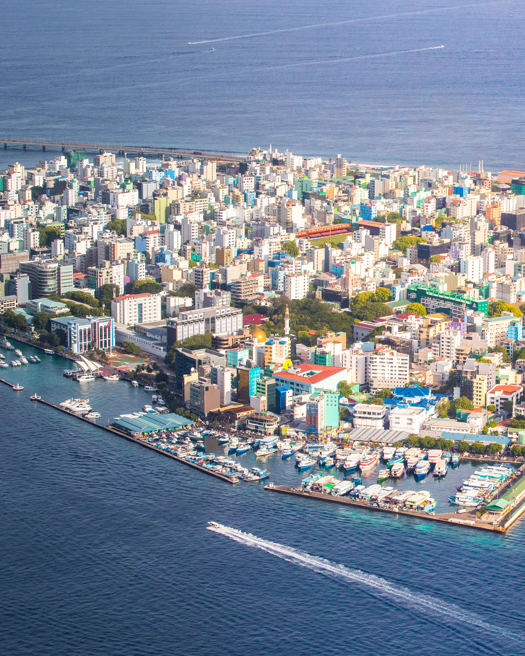 A small green island encircled by bright turquoise water in the Maldives