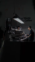 Barista carefully pouring espresso into a minimalist matte black cup under soft industrial lighting.
