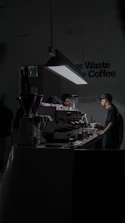 Minimalist counter with a barista preparing a latte, surrounded by black and brown decor.