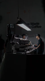 Close-up of a barista brewing coffee with an Aeropress in a minimalist industrial setting.