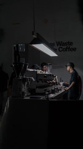 Barista carefully pouring espresso into a minimalist matte black cup under soft industrial lighting.
