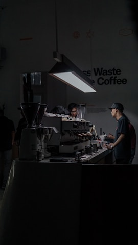 Trainer guiding a group through a hands-on coffee brewing workshop in a bright, welcoming space.