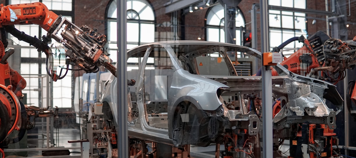 gray vehicle being fixed inside factory using robot machines