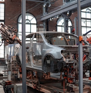 gray vehicle being fixed inside factory using robot machines