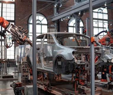 gray vehicle being fixed inside factory using robot machines