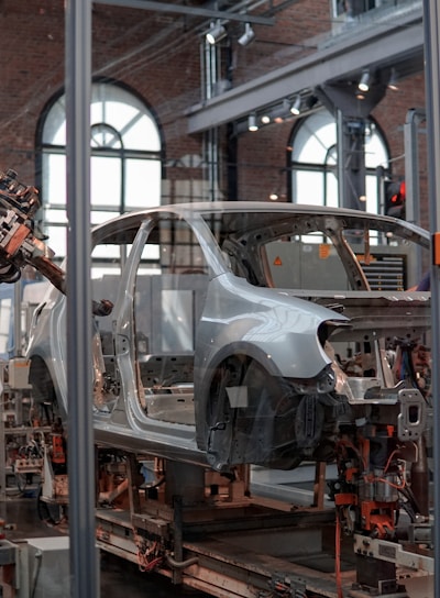 gray vehicle being fixed inside factory using robot machines